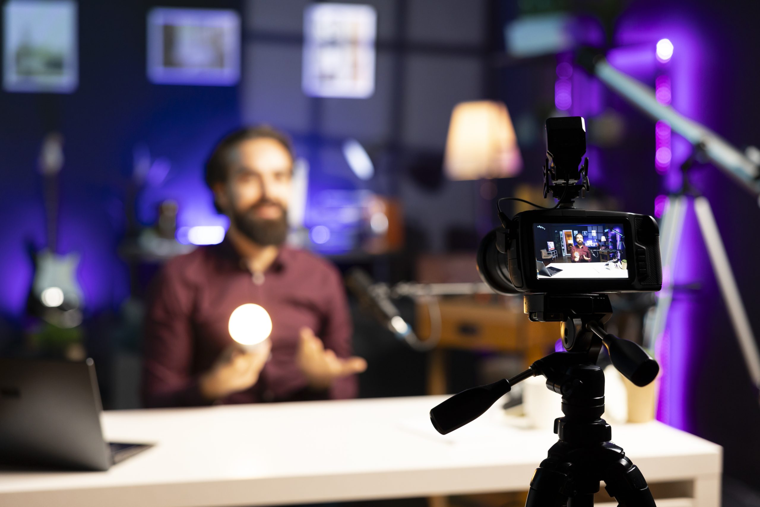 smiling tech guru reviewing smart light bulb in studio