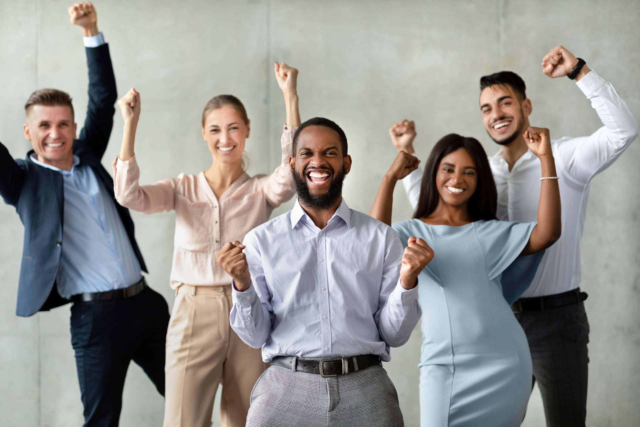 successful team. group of multiracial colleagues celebrating business achievement with raised fists