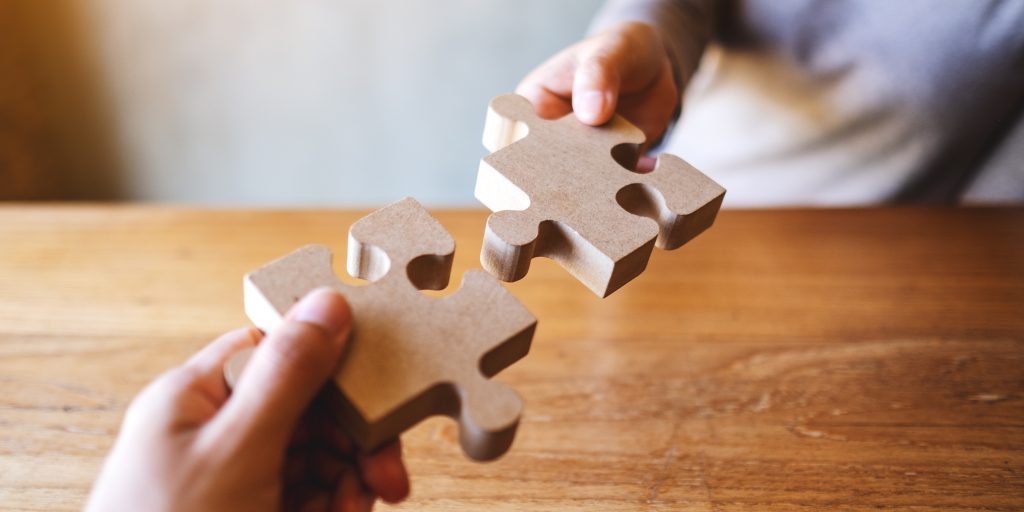 closeup image of two people holding and putting a piece of woode