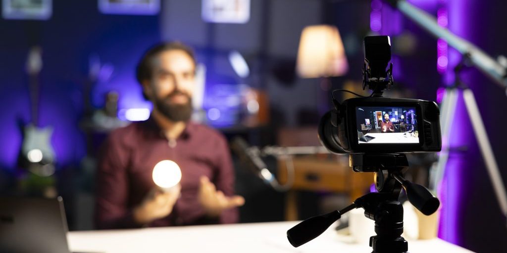 smiling tech guru reviewing smart light bulb in studio